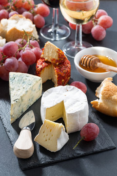 molded cheeses, wine and grapes on a blackboard