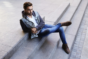 Young man relaxing on step, looking away