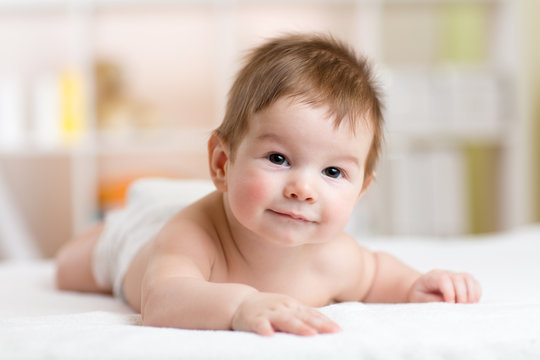Portrait of a three months old baby on the bed in nursery room
