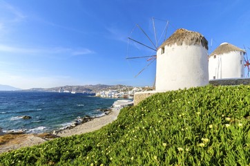 Three windmills in Chora,Mykonos,Greece.Traditional greek whitewashed architecture,popular landmark,tourist destination against blue sky and Aegean sea over Little Venice.Wind mills are now decorative © f8grapher
