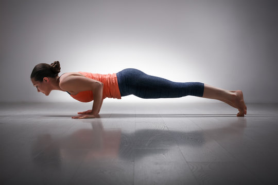 Woman practices yoga asana Chaturanga Dandasana