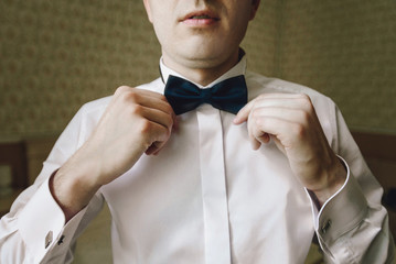 gorgeous happy luxury stylish groom getting ready on the backgro