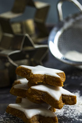 Zimtsterne gestapelt mit Backzutaten, Haarsieb und Puderzucker