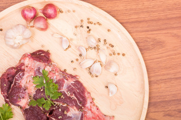 fresh raw beef meat slices and garlic, pepper on wooden