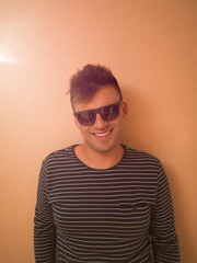 Portrait of happy hipster wearing sunglasses against color backg