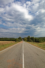 Fototapeta premium Asphalted road against the blue sky with clouds.