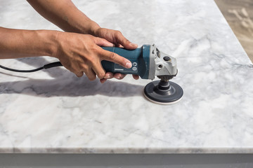 Man polishing marble table by angle grinder
