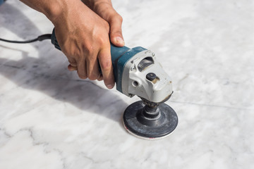 Man polishing marble table by angle grinder