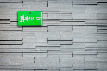 Green fire exit sign on stone wall