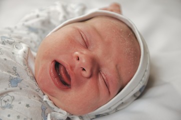 Newborn boy crying and yelling at the cradle.