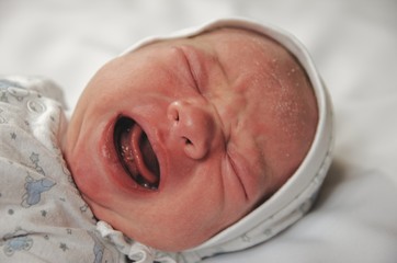 Newborn boy crying and yelling at the cradle.