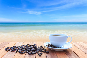 White coffee cup and coffee beans on wood table and view of suns