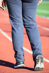 Fototapeta na wymiar Rear close-up view of female sportsman legs wearing sports shoes, running lane on stadium