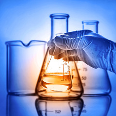 Flask in scientist hand with laboratory background 