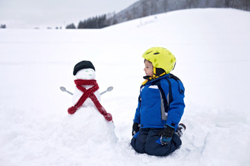 Fototapeta na wymiar Happy little boy playing in the snow while snowing, helmet