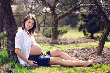 Naklejka na ściany i meble Young pregnant woman against blossoming tree in spring