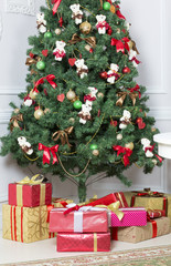 Christmas tree decorated with toys. Gifts lie under the tree.