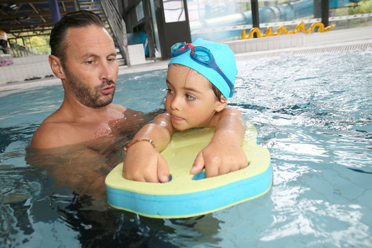 Boy child learning to swim with trainer