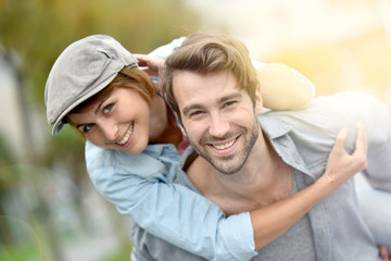 Fototapeta premium Portrait of man giving piggyback ride to girlfriend