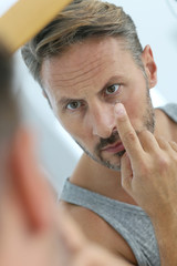 Closeup of middle-aged man inserting contact lens