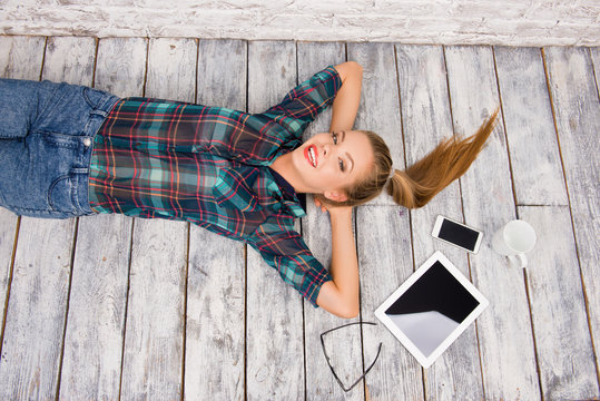 Good-looking girl with tablet, phone and cup lying on the floar