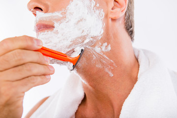 Closeup photo of a man with towel  shaving himself with a razor