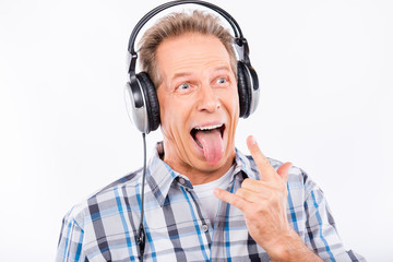 Funny cheerful aged hipster with headphones showing tongue
