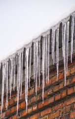 Сосульки на краю крыши зимой застывшая вода