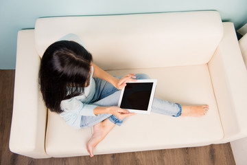 Cute young woman holding tablet sitting on the sofa