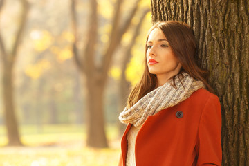 Portrait of a beautiful brunette woman in autumn park. She is looking into the distance.