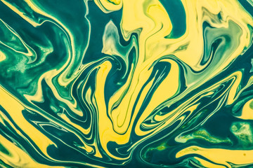 Fototapeta premium Yellow and green paint flowing and mixing texture.