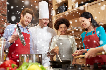 happy friends and chef cook cooking in kitchen