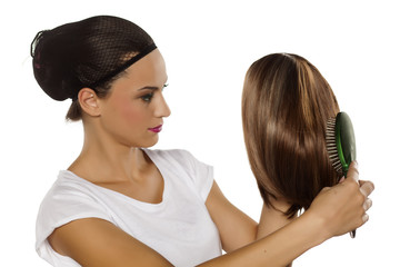 young woman with a wig cap comb her wig
