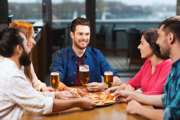 friends eating pizza with beer at restaurant