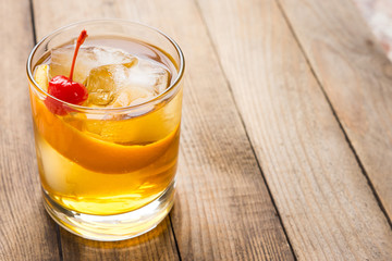 Old fashioned cocktail with cherry and orange peel