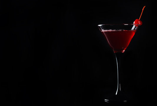 Red cocktail with cherry isolated on the black background