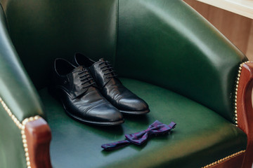 male shoes and bow-tie on green armchair