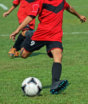 Young soccer player kicks the ball