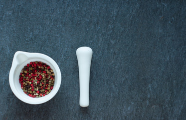 white china mortar with color pepper on stone background
