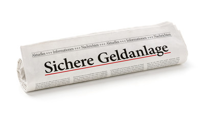 Zeitungsrolle mit der Überschrift Sichere Geldanlage