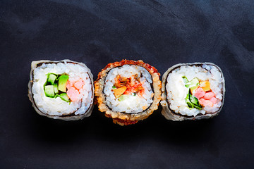 Three colorful sushi on black with copyspace