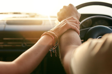 Couple traveling by car and holding hands