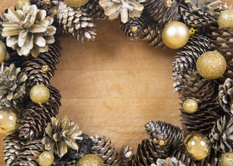 Fototapeta na wymiar Christmas wreath of cones and balls on wooden surface.