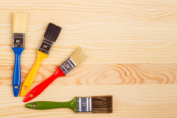 Set of colored brushes for repairs on a wooden background
