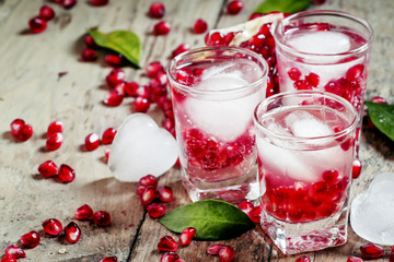 Fresh sparkling water with ice and pomegranate, selective focus