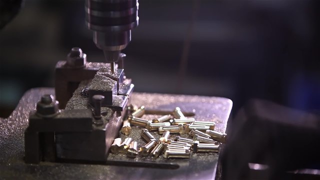 hands rapidly changing details in the boring machine. It looks like a bullet or bullets for the weapon. Factory production of weapons and ammunition, ammo