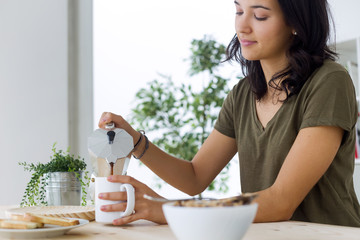 Beautiful young woman enjoying breakfast at home.