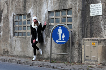 Beautiful woman with bobble hat next to a traffic sign for pedestrians