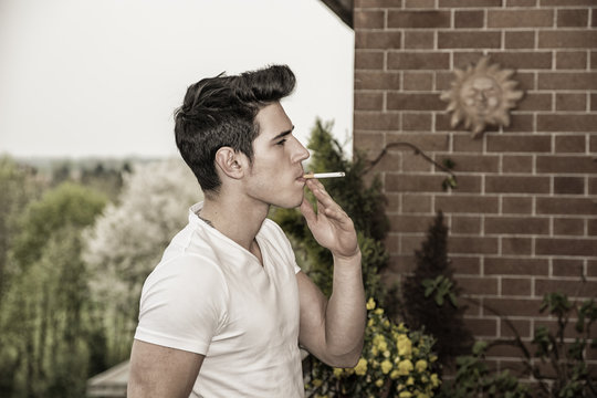 Handsome young man smoking a cigarette outside