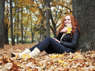 redhead girl with leaf in city park, fall season